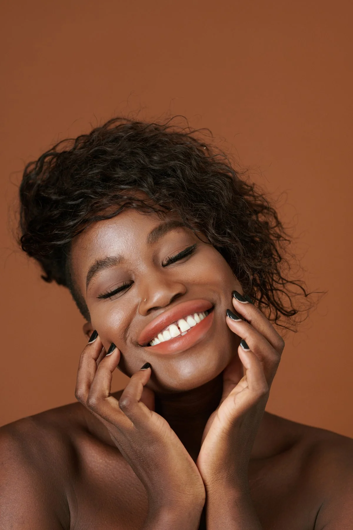 Smiling woman with bright, even teeth touching her face